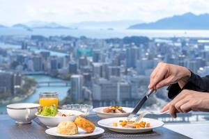 a person eating food on a table with a view at Rihga Royal Hotel Hiroshima in Hiroshima