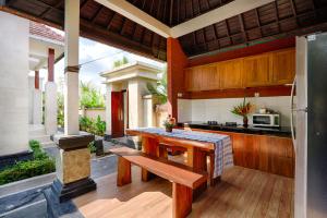 an outdoor kitchen with a wooden table and a bench at Kubu Kapas Bali in Ubud