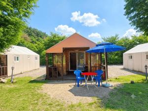 a tiny house with two chairs and an umbrella at Cheongdo Apa Camp in Cheongdo