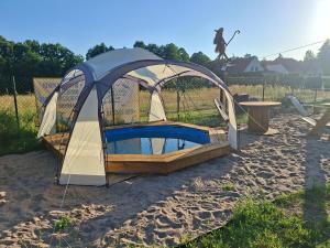 a tent on the sand with a woman jumping into it at Czarci Zakątek in Pozezdrze