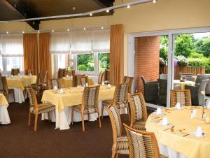 a dining room with tables and chairs and windows at Wolfsburg Sandkamp Hotel by Belvilla in Wolfsburg