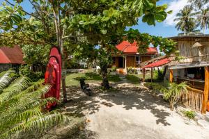 a house with a red fence and a tree at Likat Surf House in Tua Pejat
