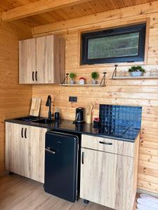 a kitchen with a black refrigerator and wooden walls at Panorama Sarpi 2 in Batumi
