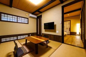 a living room with a wooden table and a television at Yufuin Ryokan Yufumomiji in Yufu