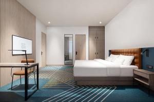 a bedroom with a bed and a table and a desk at Four Points by Sheraton Jakarta Thamrin in Jakarta +57 photos