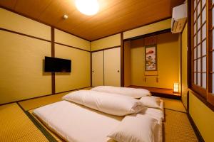 a room with two beds and a flat screen tv at Yufuin Ryokan Yufumomiji in Yufu +124 photos