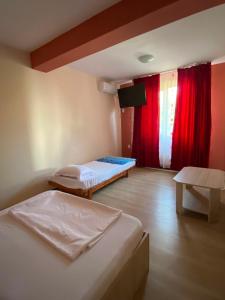 two beds in a room with red curtains at Casa Didina in Năvodari +5 photos
