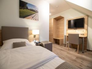 a bedroom with a bed and a desk with a television at Wolfsburg Fallersleben Hotel by Belvilla in Wolfsburg