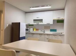 a kitchen with white cabinets and a table and chairs at Yun's hotel in Tongyeong