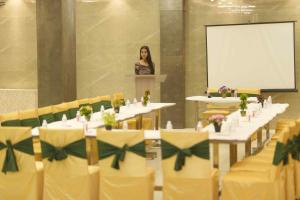 a woman is standing at a podium in a room with tables at Hotel Sopan Heights in New Delhi