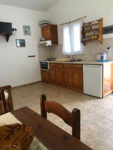 a kitchen with wooden cabinets and a table and a refrigerator at Aidonofolies in Koukounaries