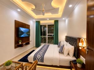 a bedroom with a bed and a tv on the wall at Sitara Premium Gangotri Palace, Tapovan in Rishīkesh