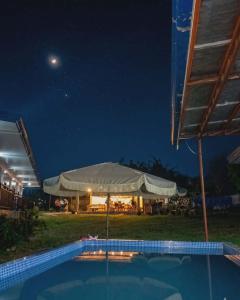 a swimming pool at night with an umbrella at Veronica Palms in Pooc