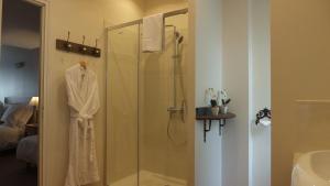 a bathroom with a shower with a robe on it at Hotel La Closeraie in Sully-sur-Loire +51 photos