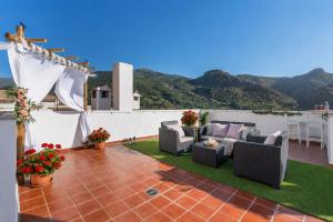 a patio with couches and flowers on a roof at Studio with Terrace & Stunning Views in Güéjar-Sierra