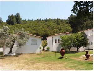 a couple of white buildings with trees in the background at Aidonofolies in Koukounaries