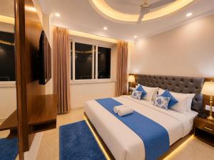 a bedroom with a large bed with blue pillows at Sitara Premium Gangotri Palace, Tapovan in Rishīkesh +29 photos