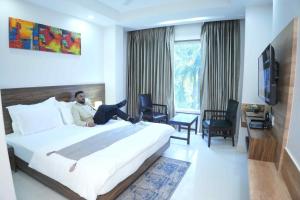 a man sitting on a bed in a hotel room at Hotel Sopan Heights in New Delhi