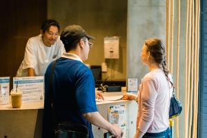 a man and a woman standing at a counter at BESTIE - Doyanen Hotels in Osaka