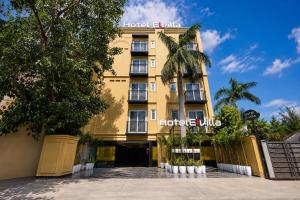 a yellow building with palm trees in front of it at Hotel Elvilla Model Town in New Delhi