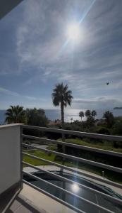 a balcony with a view of the ocean and a palm tree at Taormina Belu Beach Apartment in Letojanni