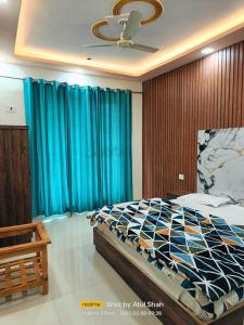 a bedroom with a large bed with blue curtains at Hotel Ajay Palace in Pīpalkoti