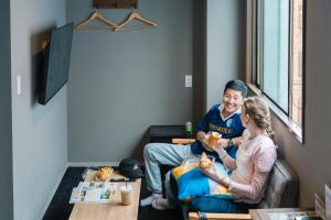 a man and woman sitting in a room eating food at BESTIE - Doyanen Hotels in Osaka