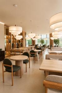 a restaurant with tables and chairs and lights at Baitau Hotel Aktobe in Aktobe