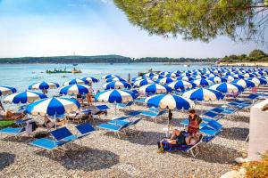 a bunch of chairs and umbrellas on a beach at Villa Vida, Medulin - Bazen i jacuzzi in Medulin