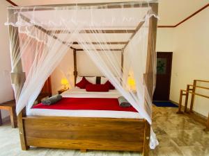 a bedroom with a canopy bed with red pillows at Rawana Mountain View Homestay in Ella
