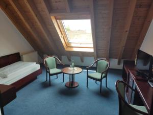 a room with a bed and a table and chairs at Hotel Waldhorn in Friedrichshafen