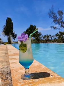 a drink sitting on a table next to a swimming pool at Antsanitia - Domaine du Mandravasarotra - DDM in Antsianitia