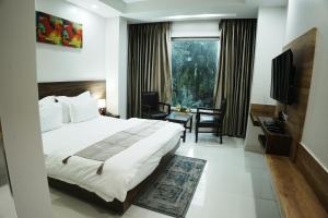 a bedroom with a bed and a desk and a television at Hotel Sopan Heights in New Delhi +48 photos