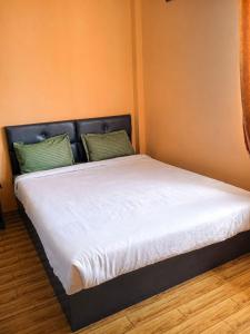 a bed with white sheets and two green pillows at Perfect View Homestay in Cherrapunji
