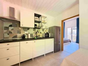 a kitchen with white cabinets and a stainless steel refrigerator at Pansion Palme in Drvenik