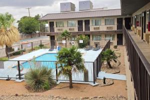 an apartment building with a swimming pool and palm trees at Howard Johnson by Wyndham Odessa TX in Odessa