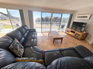 a living room with a leather couch and a flat screen tv at Ocean Shores Apartment 15 - Bring your own linen. in South West Rocks