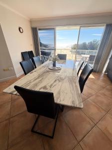a dining room with a table and chairs with a view at Ocean Shores Apartment 15 - Bring your own linen. in South West Rocks