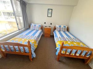 two twin beds in a room with a window at Ocean Shores Apartment 15 - Bring your own linen. in South West Rocks +14 photos