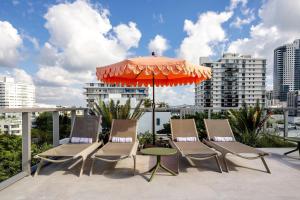a group of chairs and an umbrella on a balcony at Dolce by Wyndham Miami Beach in Miami Beach