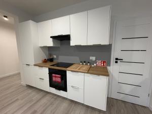 a white kitchen with white cabinets and a wooden floor at Modern 2023 apartment in Kutno