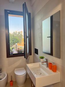 a bathroom with a sink and a toilet and a window at Sole di Sicilia in Locogrande +55 photos