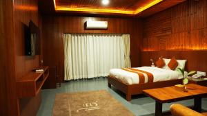 a bedroom with a bed and a table and a television at ila Comfort Harkapur in Maruwā Ghāt
