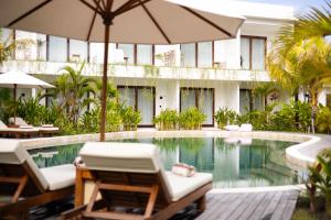 a resort pool with chairs and an umbrella at Uryah Hotel Lombok in Selong Belanak