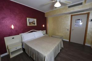 um quarto com uma cama e uma parede roxa em New Automatic Villa Daniela em San Bartolomeo al Mare