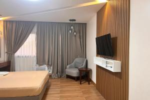 a hotel room with a bed and a chair and a television at NSCC Stella Maris Hotel & Convention Center in Cabugao