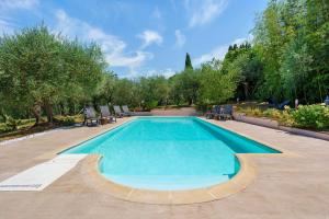 a large swimming pool with chairs and trees at Agriturismo Santa Luce in Foiano della Chiana