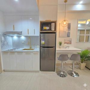 a kitchen with a refrigerator and two bar stools at Jade Mantle Sanctuary in Manila