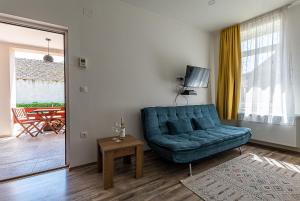 a living room with a blue couch and a television at Adamkó Borkert Ház in Villány