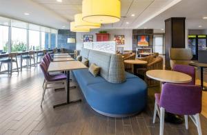 a cafeteria with tables and chairs and a blue couch at Home2 Suites by Hilton Gillette in Gillette